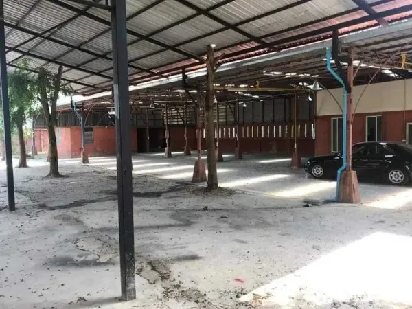 Warehouse for rent or sale in Khlong Sam Wa, Bangkok - Open-air warehouse with steel roof, concrete floor and brick perimeter, featuring a small office bay.