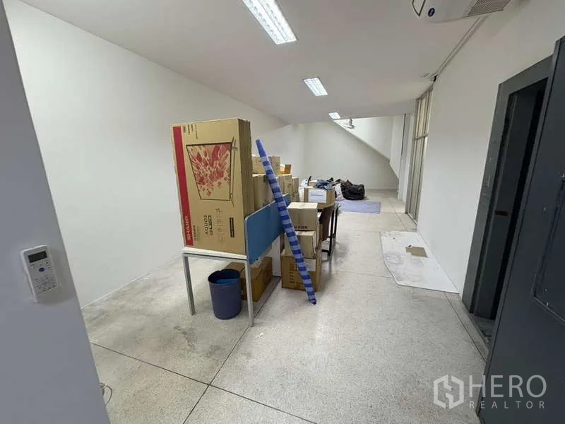 Office Space for rent in Khlong Toei, Bangkok - Storage or workroom with boxes, ladder and high windows.