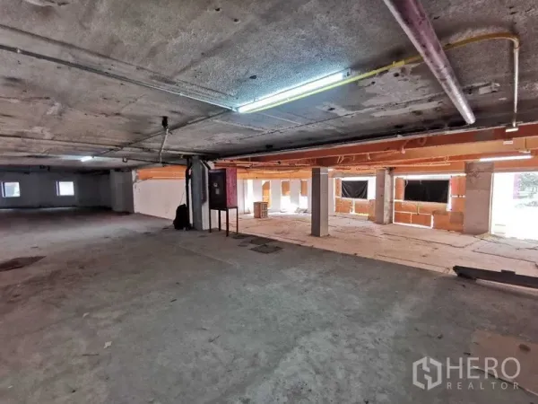 Retail Space for rent in Khlong Toei, Bangkok - Spacious shell retail interior with exposed ceiling, concrete floors, pillars, and fluorescent lighting.