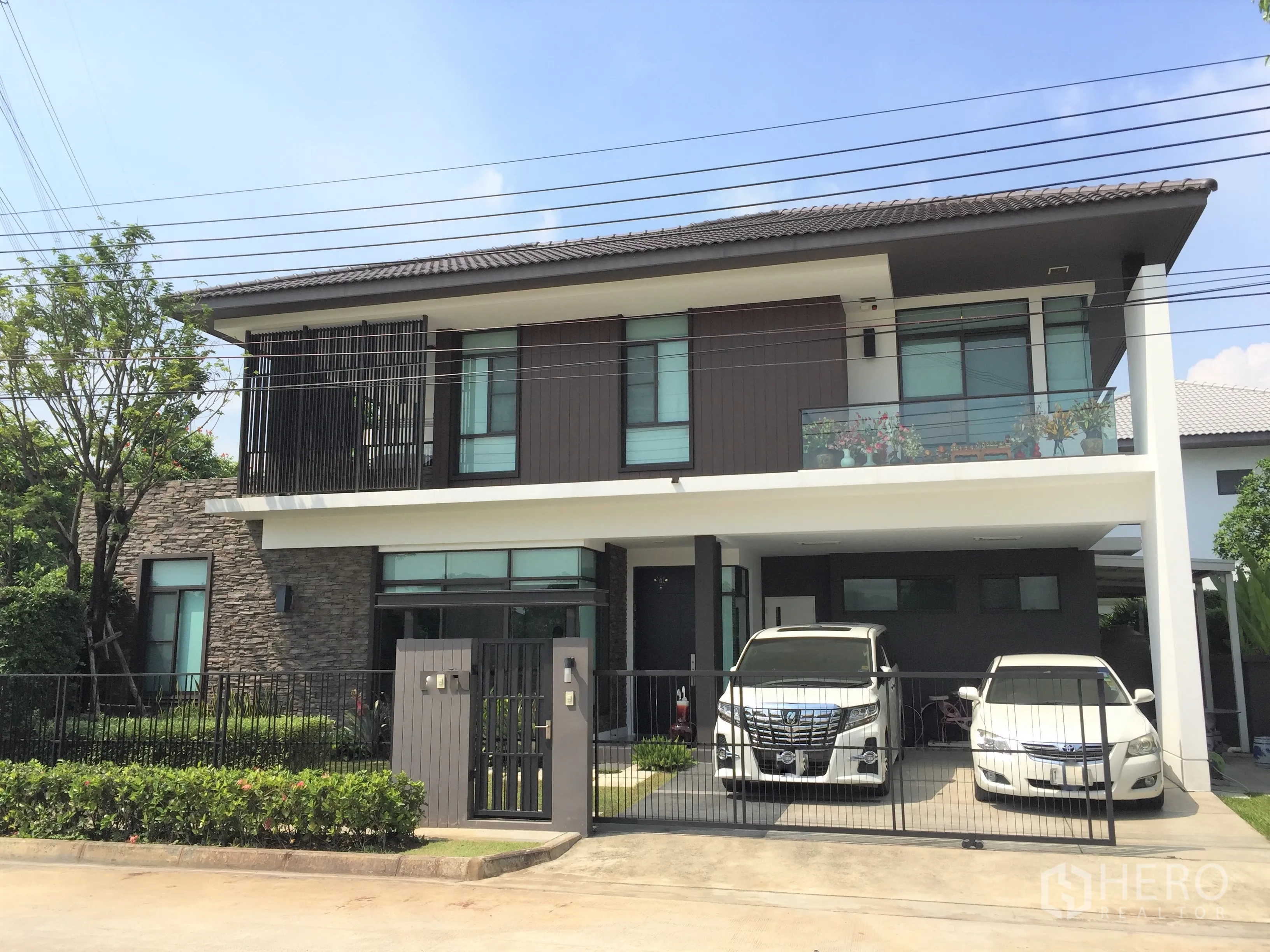 Detached House for rent or sale in Prawet, Bangkok - Modern two-storey detached house with stone accents, balcony and gated two-car carport.