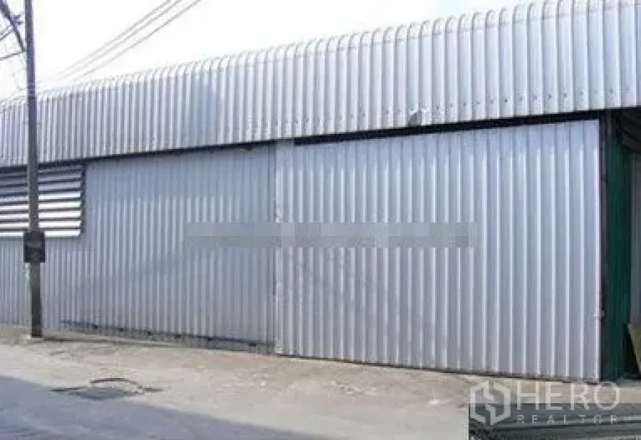 Warehouse for rent in Suan Luang, Bangkok - Street-facing corrugated metal warehouse exterior with wide sliding steel door in Suan Luang, Bangkok.
