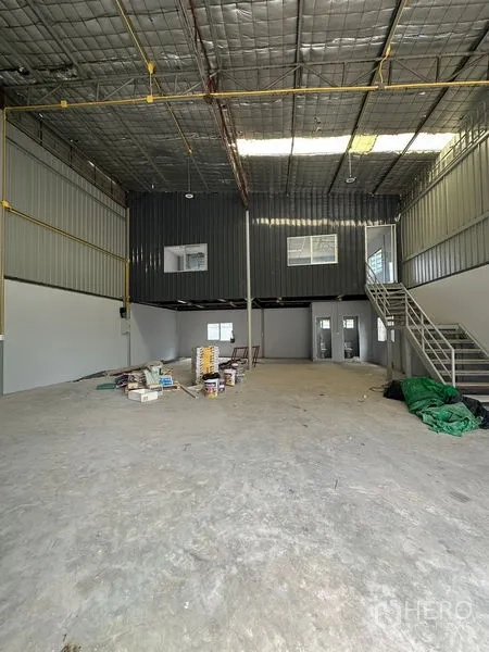 Warehouse for rent in Suan Luang, Bangkok - High-ceiling warehouse interior with insulated roof, mezzanine office, metal staircase and open concrete floor.