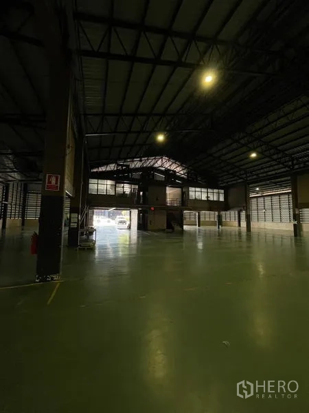 Warehouse for rent in Si Racha, Chon Buri - Warehouse interior showing a mezzanine office and wide roller-door access.