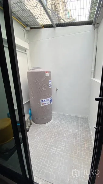 Townhouse for rent in Bang Na, Bangkok - Utility patio with water tank and tiled floor under a metal canopy.
