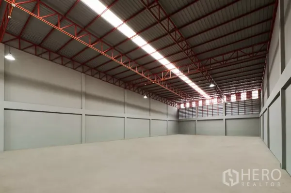 Factory for rent in Mueang Samut Sakhon, Samut Sakhon - Wide column-free factory floor with red steel truss roof and louvered vents.