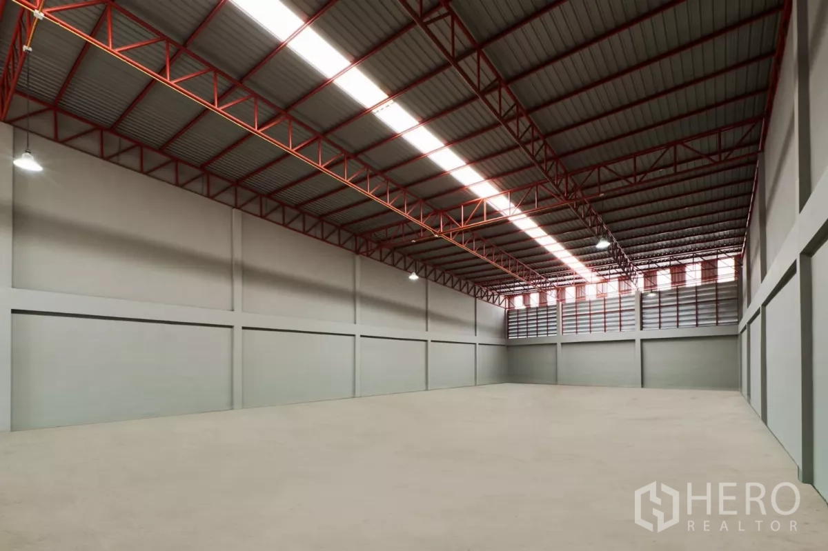 Factory for rent in Mueang Samut Sakhon, Samut Sakhon - Wide column-free factory floor with red steel truss roof and louvered vents.