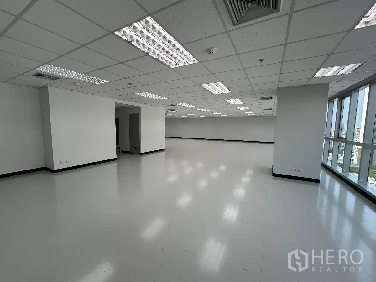 Office Space for rent in Watthana, Bangkok - Corner office floor with window frontage, structural columns, and doorway to service area, filled with natural light.