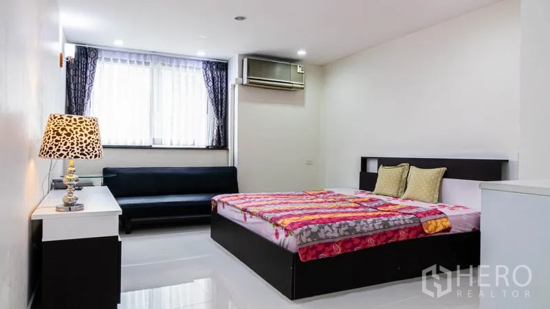 Condominium for rent or sale in Khlong Toei, Bangkok - Bedroom with double bed, sofa seating, window drapes and air conditioning.