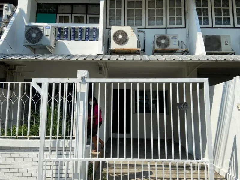 Townhouse for rent in Watthana, Bangkok - Gated townhouse facade with covered carport and multiple air-conditioning units.