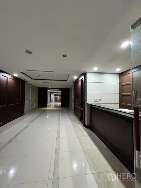 Office Space for rent in Watthana, Bangkok - Corridor beside a built-in reception desk and wood wall panels.