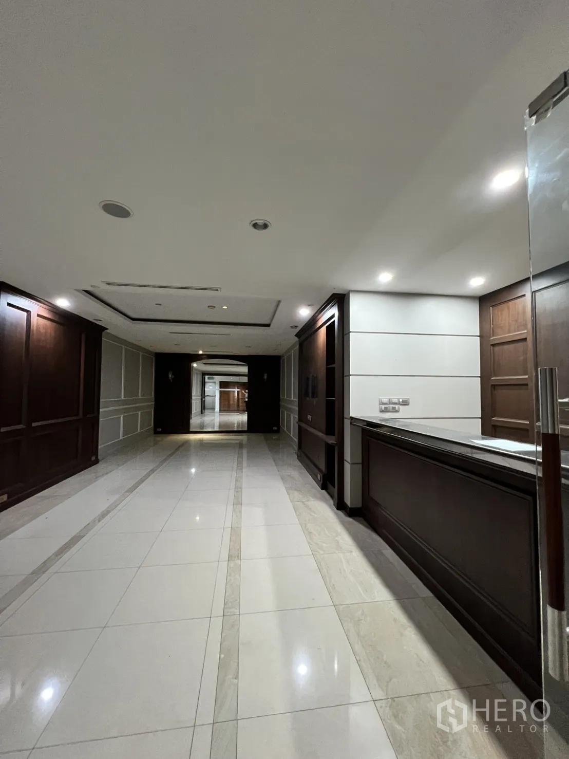 Office Space for rent in Watthana, Bangkok - Corridor beside a built-in reception desk and wood wall panels.