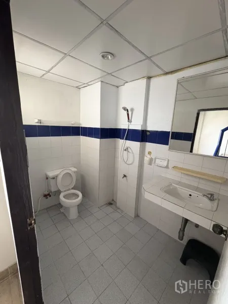 Shophouse for rent in Phra Khanong, Bangkok - Tiled bathroom with toilet, wall mirror, sink and handheld shower.