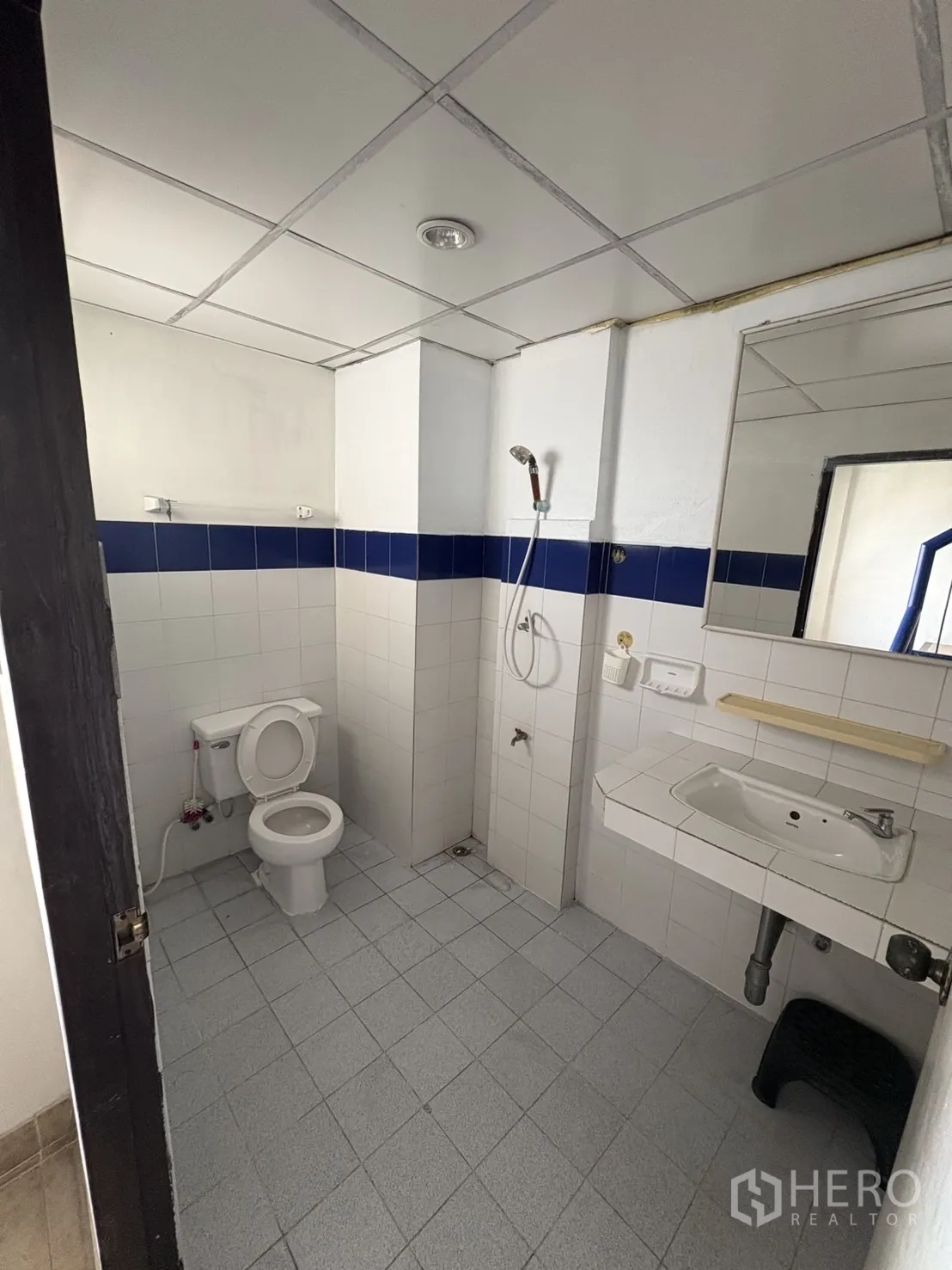Shophouse for rent in Phra Khanong, Bangkok - Tiled bathroom with toilet, wall mirror, sink and handheld shower.