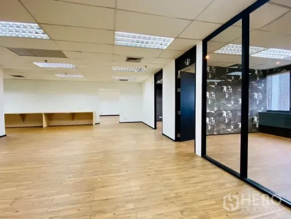 Office Space for rent or sale in Watthana, Bangkok - Open-plan workspace with glass partition, patterned feature wall and suspended ceiling lights.