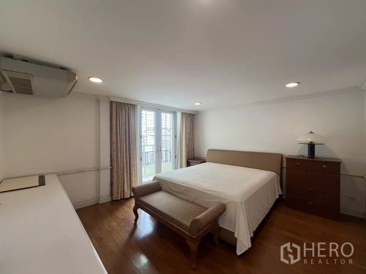Townhouse for sale in Watthana, Bangkok - Guest bedroom with bed, balcony doors and hardwood flooring.