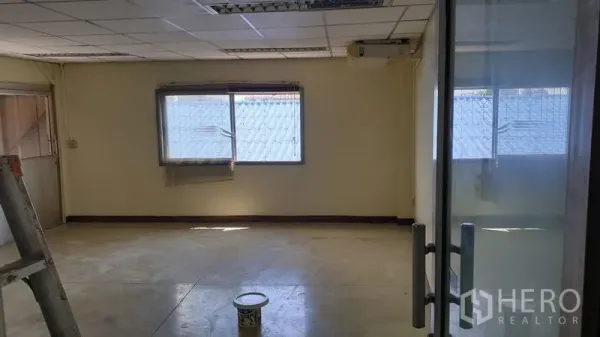 Warehouse for rent in Suan Luang, Bangkok - Empty mezzanine office room with windows, drop ceiling and a glass door.