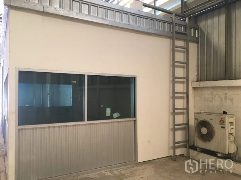 Warehouse for rent in Suan Luang, Bangkok - Ground-floor office room inside the warehouse with ladder and AC unit.
