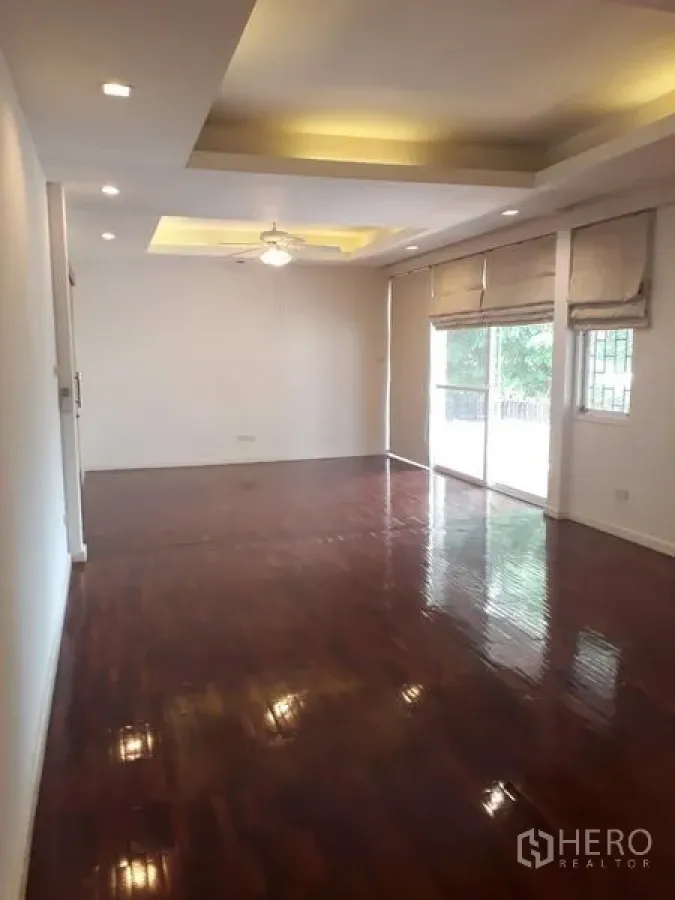 独立式住宅 出租在Watthana, Bangkok - 采光充足的客厅，灯槽吊顶与抛光木地板，推拉玻璃门通向花园
