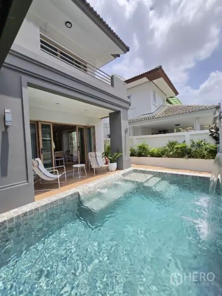 Detached House for sale in Suan Luang, Bangkok - Sparkling pool with water feature in front of a modern two‑storey facade and balcony.