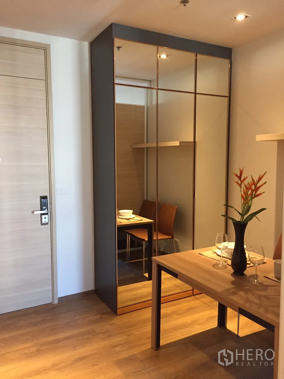 Condominium for rent or sale in Khlong Toei, Bangkok - Mirrored wardrobe reflecting the dining table set with glassware and a flower vase.
