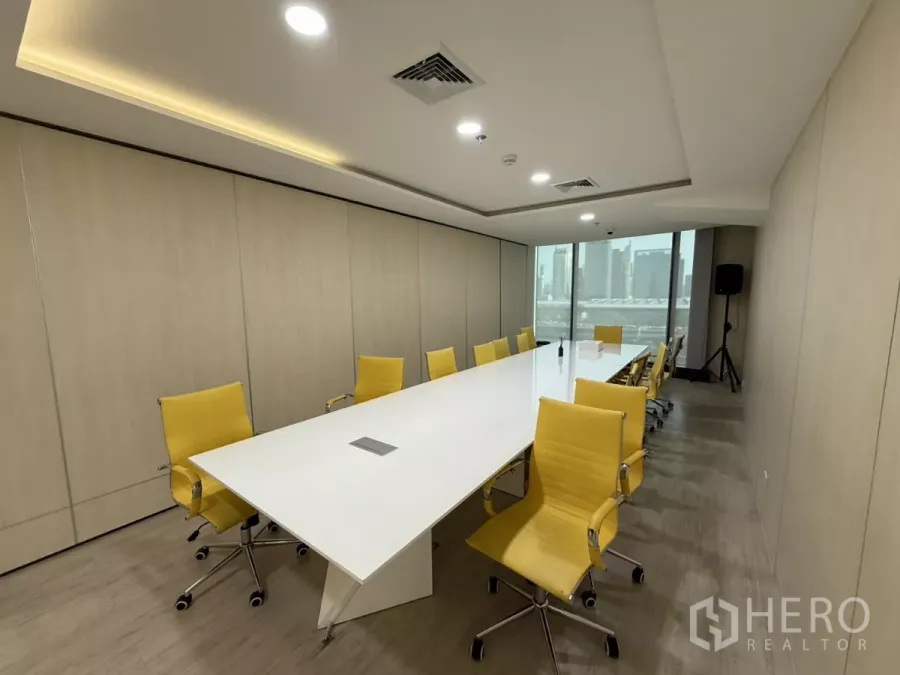 Office Space for rent in Din Daeng, Bangkok - Contemporary boardroom with a long white conference table, yellow chairs, recessed lighting and city views through large windows.