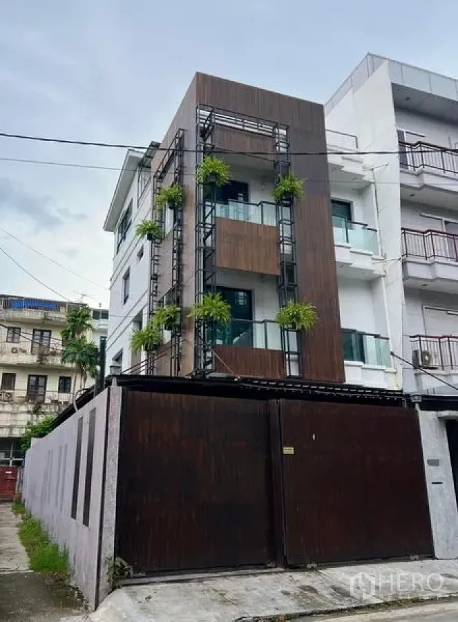 联排别墅 出租在Phaya Thai, Bangkok - 现代联排别墅正立面，木质护墙、阳台与绿植点缀。