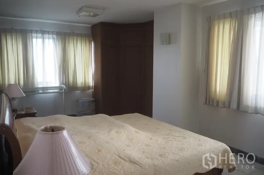 Condominium for rent in Pathum Wan, Bangkok - Sunlit bedroom with large windows, built-in corner wardrobe and a queen bed.