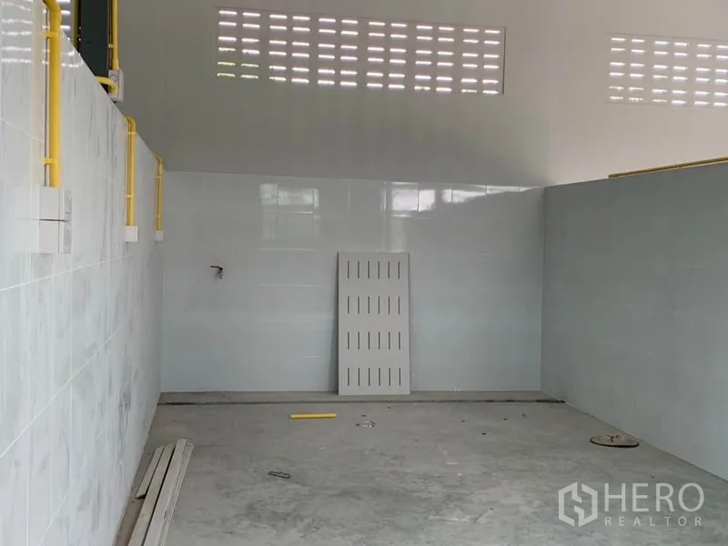 Warehouse for rent or sale in Thanyaburi, Pathum Thani - Aisle between tiled partitions under a metal roof with natural airflow blocks.