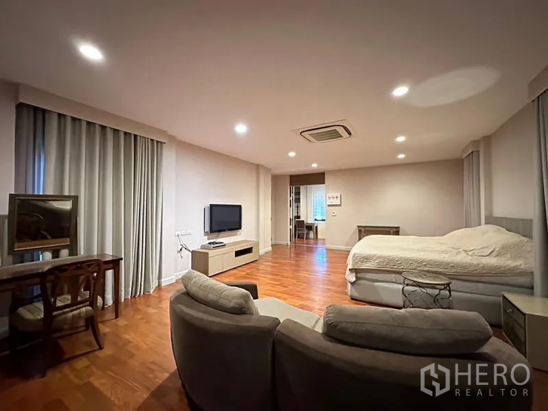 Detached House for rent or sale in Khan Na Yao, Bangkok - Master suite lounge with TV console, armchairs and floor-to-ceiling curtains.