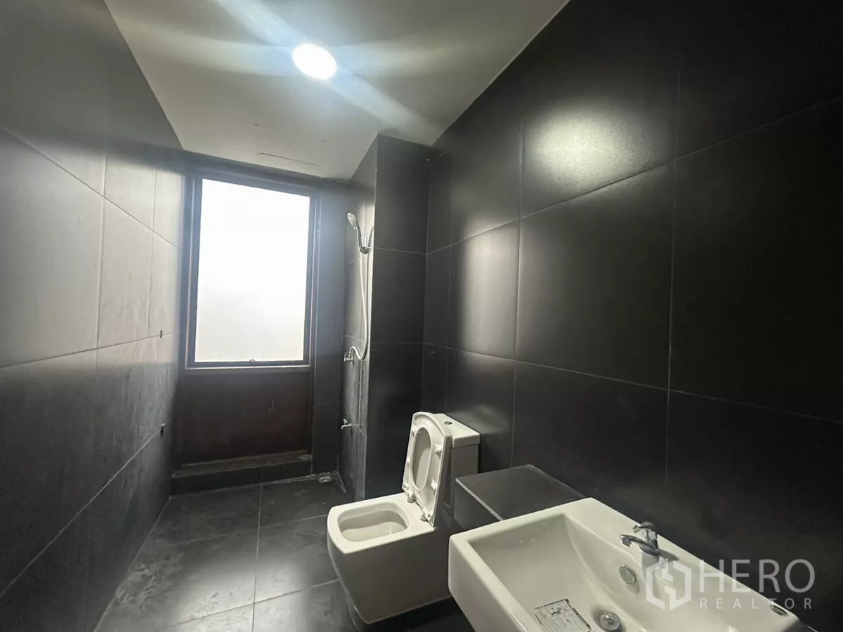 Home Office for rent in Pathum Wan, Bangkok - Black-tiled bathroom with frosted window, shower, toilet and basin.
