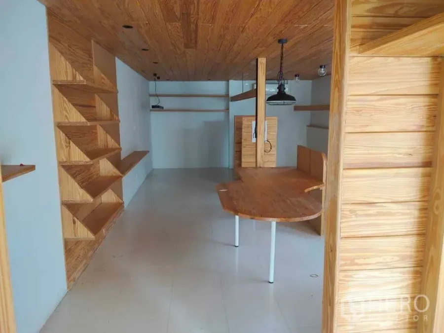 Office Space for rent in Khlong Toei, Bangkok - Office interior with zigzag built-in shelving, a curved table, wood ceiling, and light tile flooring.