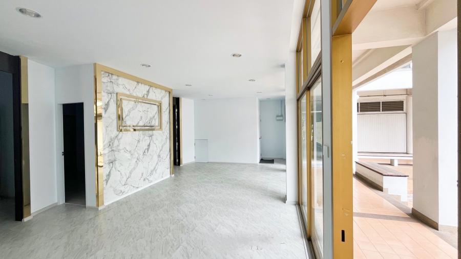 Retail Space for rent in Watthana, Bangkok - Sales floor with tiled flooring, marble feature wall and full-height glass storefront along a covered walkway.