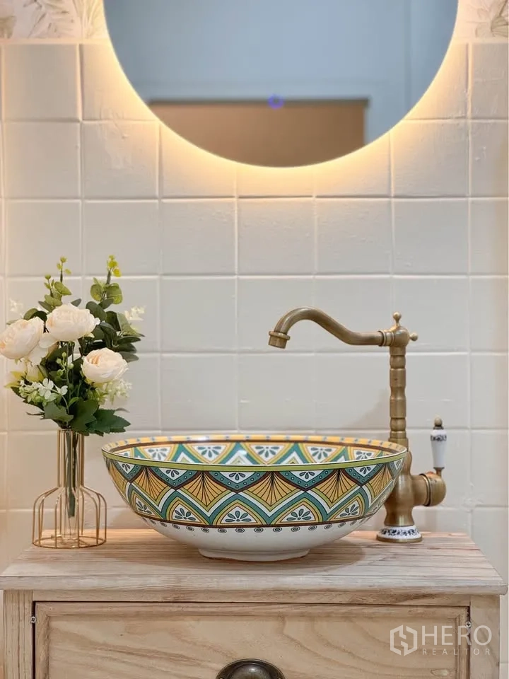 Detached House for rent in Huai Khwang, Bangkok - Close-up of patterned ceramic basin with brass faucet and backlit mirror.