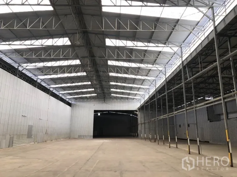 Warehouse for rent in Pak Kret, Nonthaburi - View toward a large loading opening under a high ridgeline roof with skylights and rows of side columns.