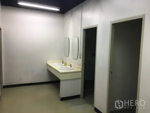 Office Space for rent in Huai Khwang, Bangkok - Restroom area featuring two sinks with mirrors and separate toilet stalls.