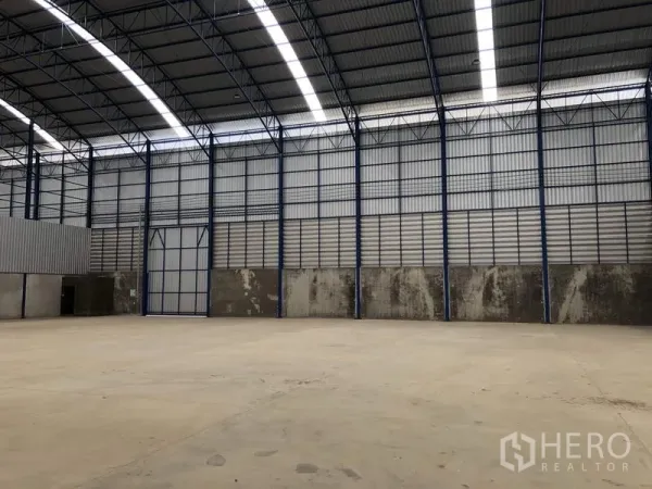 工厂 出租在Lat Lum Kaeo, Pathum Thani - 工厂内部空间宽敞，拱形钢屋顶与采光带，地面为混凝土。