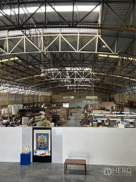 Warehouse for sale in Bang Bua Thong, Nonthaburi - Central view of the warehouse hall showing steel beams, skylights and a partitioned office.