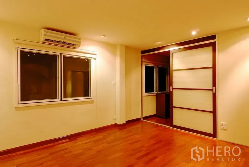 Detached House for rent in Watthana, Bangkok - Bedroom with wood flooring, split air conditioner and sliding door to the closet.