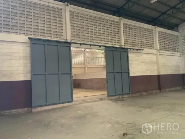Warehouse for rent in Bang Kapi, Bangkok - Interior sliding metal doors opening to an adjoining storage bay.