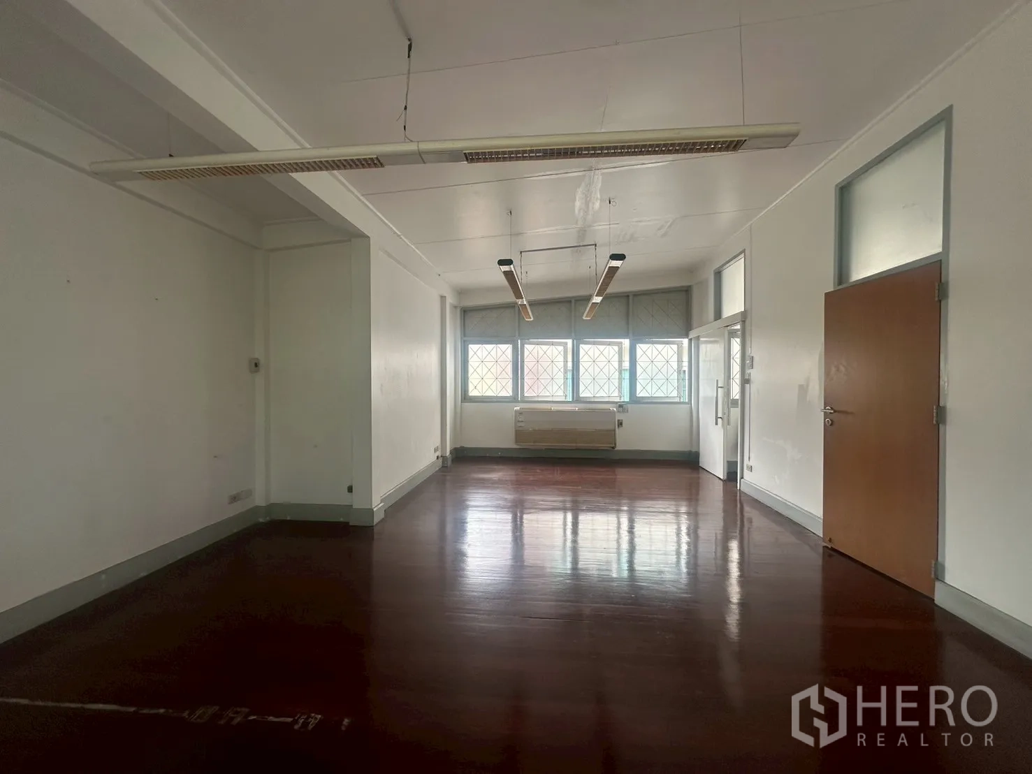 Detached House for rent in Watthana, Bangkok - Large upstairs room with polished dark wood floors and suspended strip lighting.