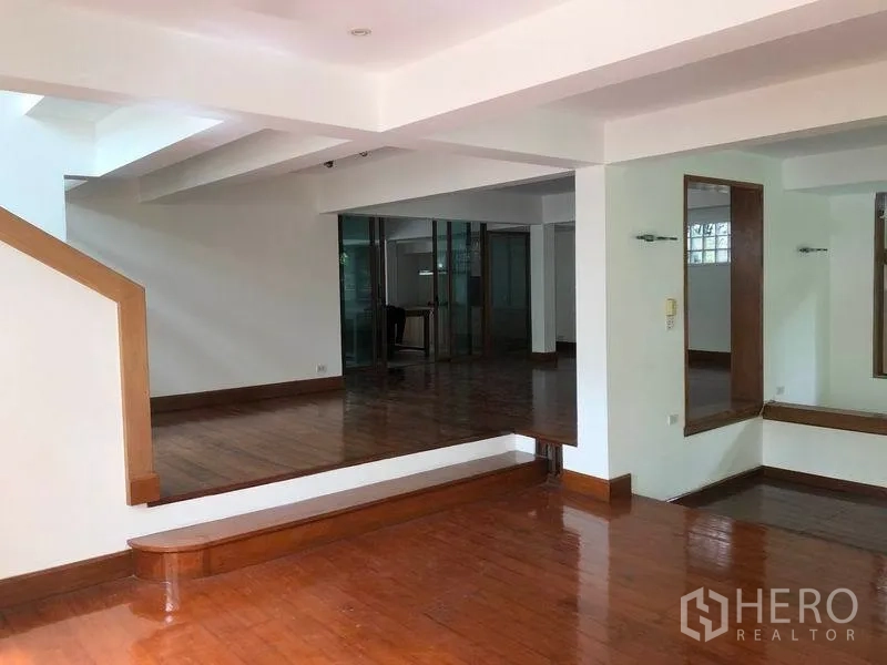 Detached House for rent in Watthana, Bangkok - Split-level lounge with staircase and glossy timber flooring.