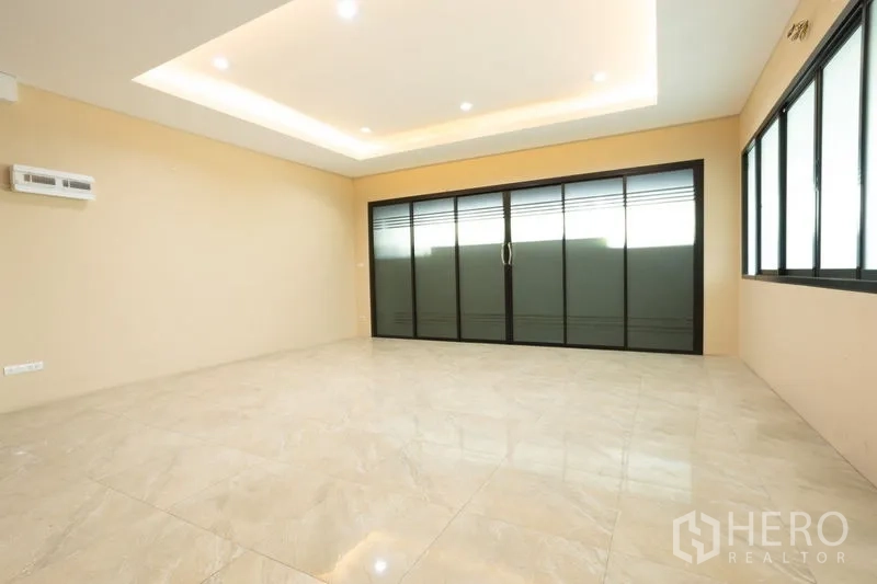 Home Office for rent in Bang Khen, Bangkok - Spacious tiled room with coved ceiling lighting and black-framed sliding glass doors.