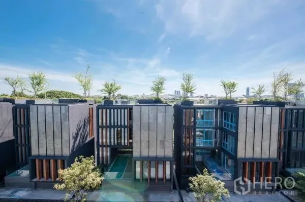 Detached House for sale in Prawet, Bangkok - Modern multi‑storey residences with vertical facades and rooftop greenery under a blue sky.
