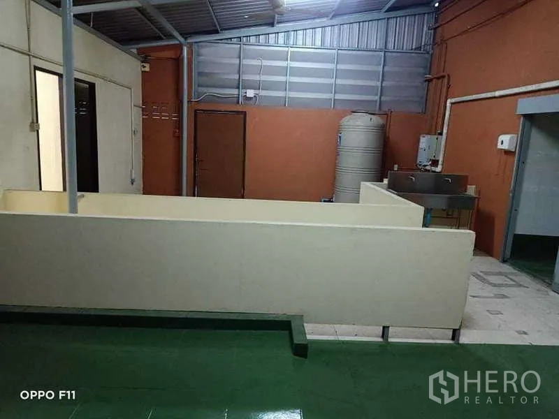 Warehouse for rent or sale in Mueang Samut Sakhon, Samut Sakhon - Semi-covered utility area with metal roof, water tank, and stainless sink.
