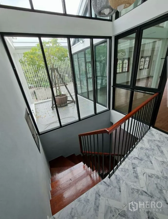 Home Office for rent in Lat Phrao, Bangkok - Stairwell enclosed by full‑height windows overlooking an internal tree courtyard.