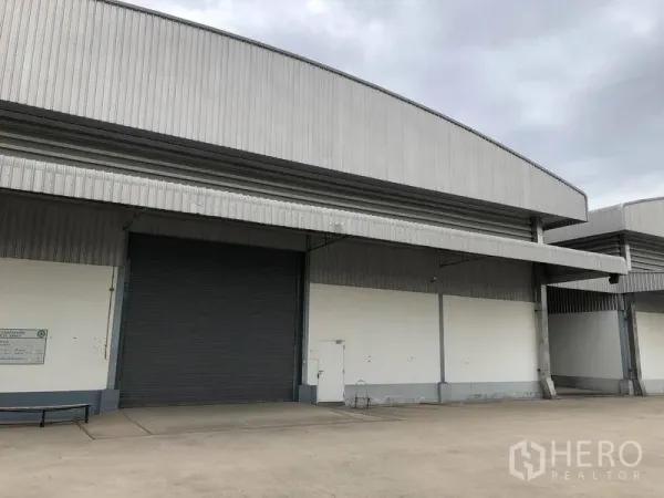 Warehouse for rent in Bang Phli, Samut Prakan - Close view of a warehouse dock showing a large roller shutter, canopy roof, and spacious loading apron for logistics operations.