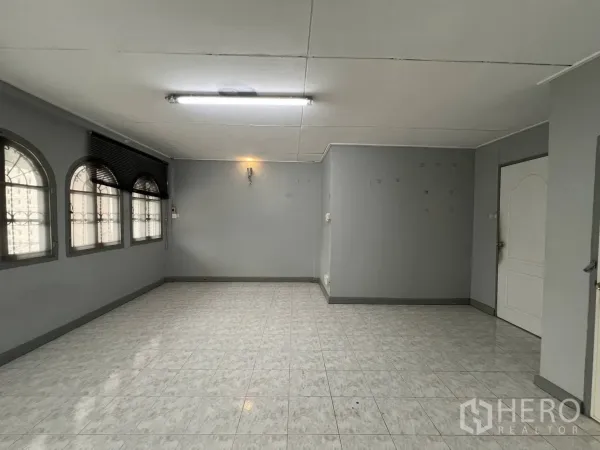 Townhouse for rent in Watthana, Bangkok - Empty living area with glossy tile floor and arched windows.