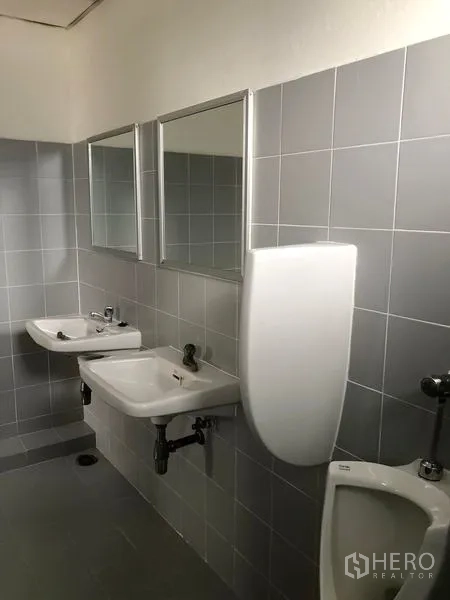 Factory for rent or sale in Bang Pa-in, Phra Nakhon Si Ayutthaya - Clean tiled restroom with wall-mounted sinks, mirrors and urinals.