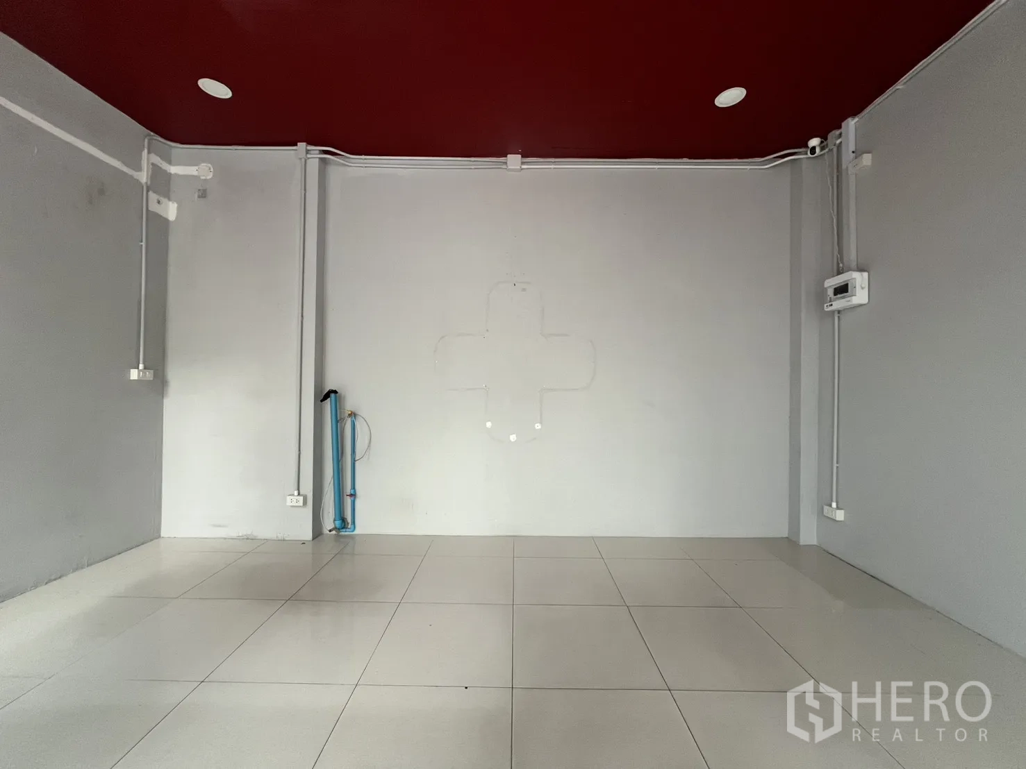 Retail Space for rent in Watthana, Bangkok - Open white-tiled sales area with maroon ceiling, power outlets and conduit ready for fit-out.