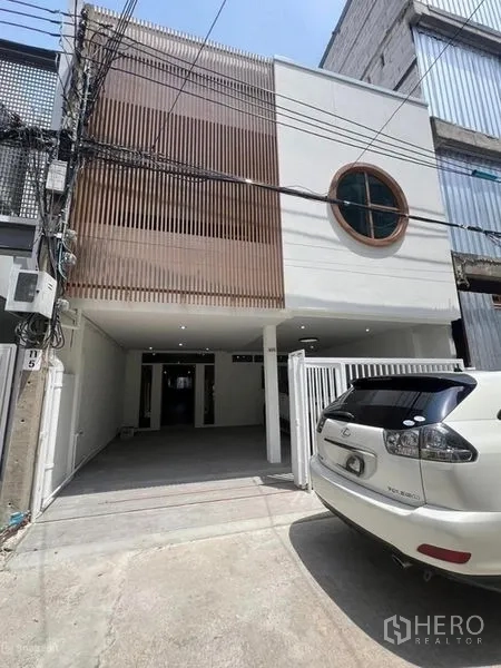 Townhouse for rent in Khlong Toei, Bangkok - Townhouse front exterior with gated parking and circular window detail.